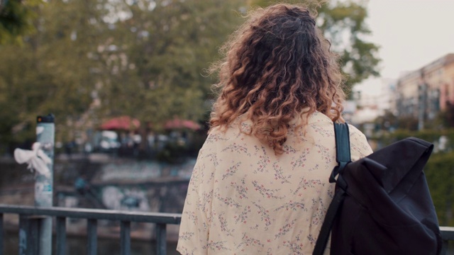 一个年轻女子在柏林的狂欢河边散步，看着鸽子视频素材
