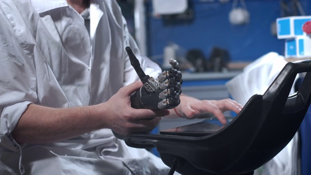 一位科学家工程师正在测试一个电子仿生假肢。他移动机械手臂的塑料手指。现代修复技术。科学家手中的控制论之手视频素材