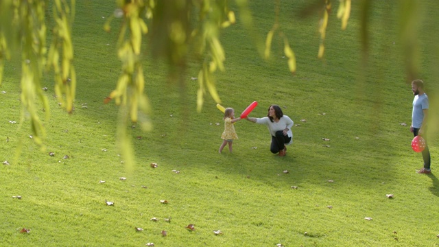 一个年轻的家庭和唐氏综合症的女儿在公园里玩气球视频素材