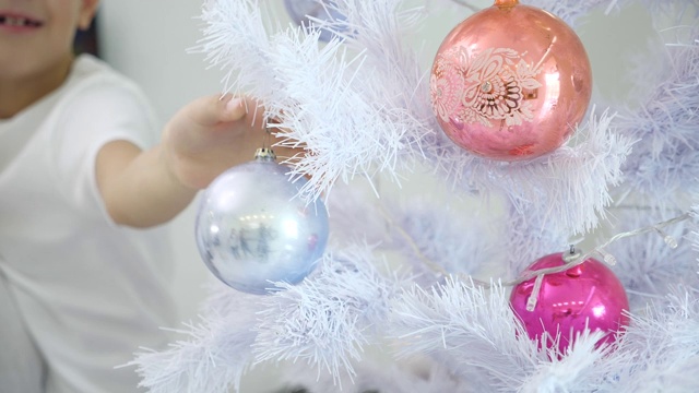 银色圣诞树上的装饰品，模糊的孩子在背景上挂着银色的玻璃球视频素材