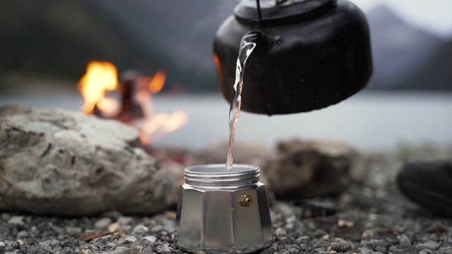 在山湖附近的户外篝火上放一个水罐视频素材