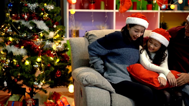 多莉拍摄微笑的父母给他们的女儿一个惊喜，在圣诞节期间送给她一个红色的带有白色丝带的圣诞礼盒视频素材