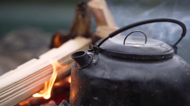蒸汽水壶在一个燃烧的壁炉户外露营特写视频素材