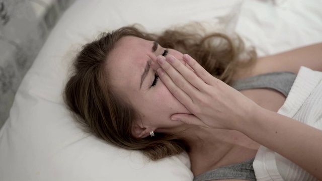 不幸的年轻女人在床上哭泣视频素材