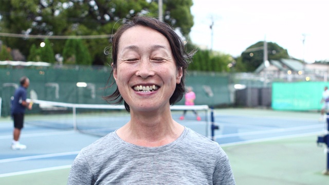 一个微笑的女子在网球场上的肖像视频素材