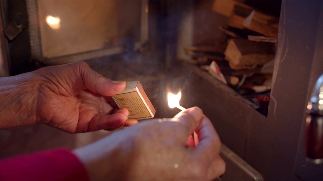 观点。一位长者在冬天点燃壁炉。庆祝的时间。壁炉与燃烧的木材特写。视频素材