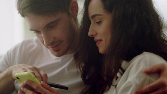 幸福的夫妇在家里一起使用手机。情侣装手机视频素材