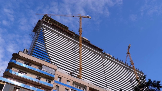 蓝天下建筑工地上的起重机正在建造新的摩天大楼。建筑施工视频素材