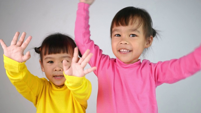 一个快乐的微笑的兄弟姐妹的孩子女孩显示挥手再见，孤立在白色的背景。视频下载