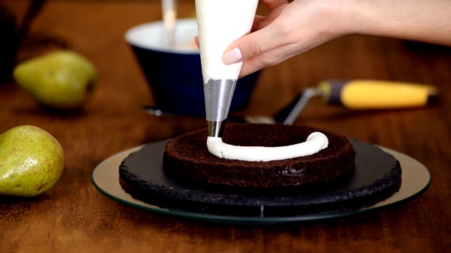 糖果女制作梨馅巧克力蛋糕。将奶油挤到蛋糕上。视频素材