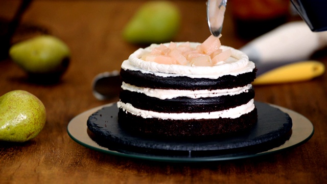 糖果女制作梨馅巧克力蛋糕。将奶油挤到蛋糕上。视频素材