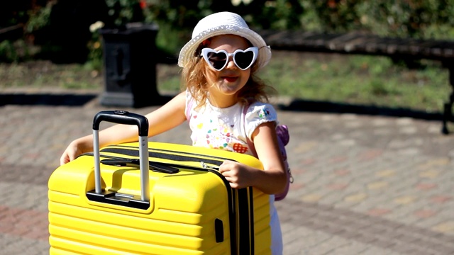 大行李。带着黄色行李箱的女游客。等待旅行的孩子。视频下载