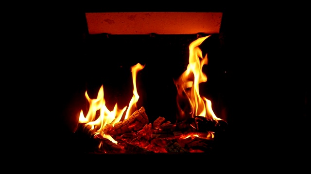 这是一个令人惊叹的特写镜头，红色和黄色的火叉覆盖在壁炉里的热木炭和木头上。看起来不可思议的。视频下载