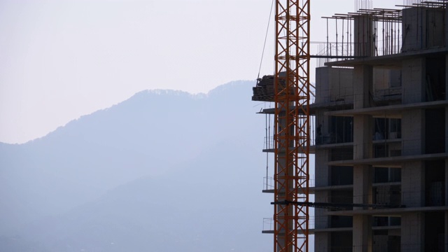 建筑工地上的塔式起重机在高层建筑中吊装重物视频素材