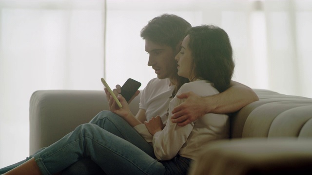 幸福的夫妇在家里看手机的特写。放松的人的肖像视频素材