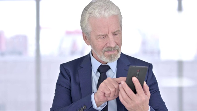 轻松的老商人使用智能手机的肖像视频素材