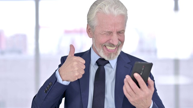 老商人庆祝智能手机成功的肖像视频素材