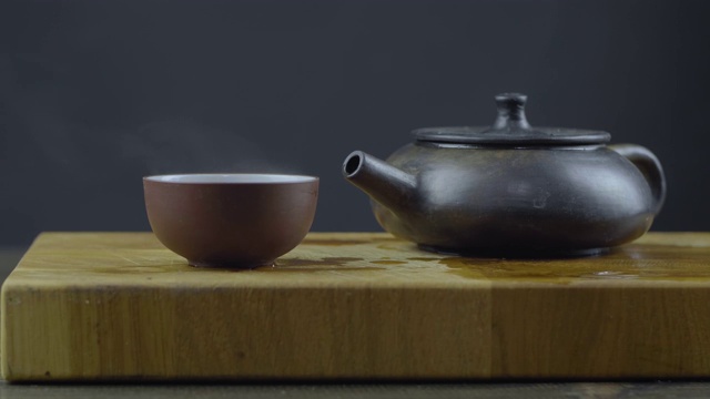 手工制作的宜兴砂茶壶，用木板上的碗盛热茶。4 k的视频。59.94帧/秒视频下载