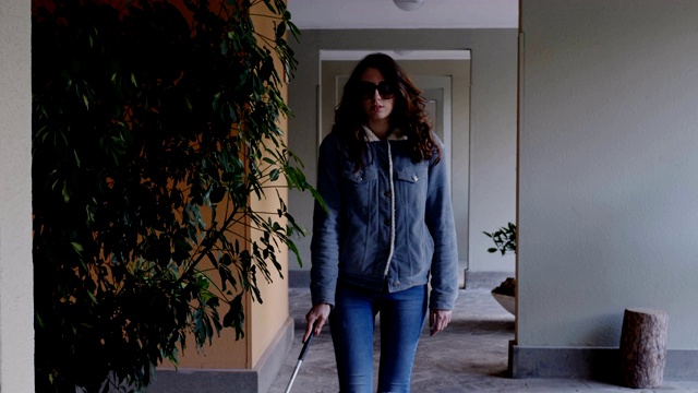 这是一个年轻独立的盲人妇女在户外拄着拐杖走路的肖像视频素材
