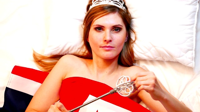 一个美丽的女孩，带着皇家权杖和皇冠躺在英国国旗上视频下载