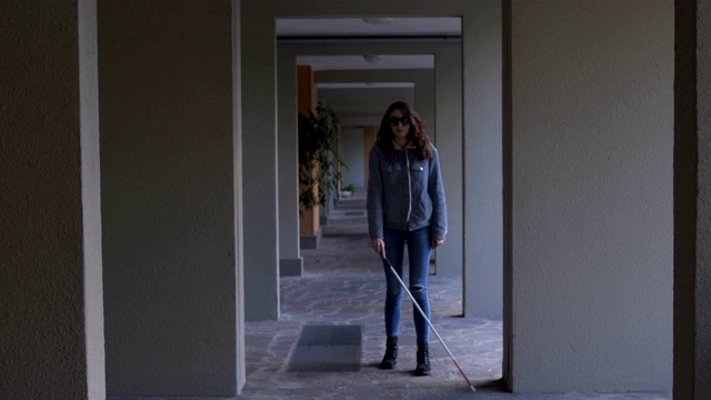 这是一个年轻独立的盲人妇女在户外拄着拐杖走路的肖像视频素材