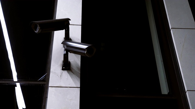 一对黑色的监控摄像头安装在一栋办公楼的墙上视频素材