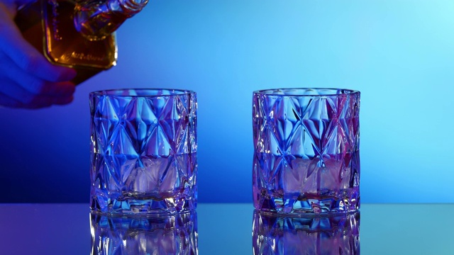 将威士忌从瓶子倒入加冰的玻璃杯中视频下载