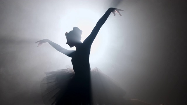 在明亮的霓虹灯聚光灯的背景下，身着芭蕾舞裙的芭蕾舞女演员的独唱。剪影的女人在尖头鞋跳舞的古典运动。4 k。视频购买