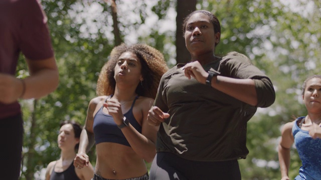 一群女运动员一起在森林里的小路上跑向镜头视频下载