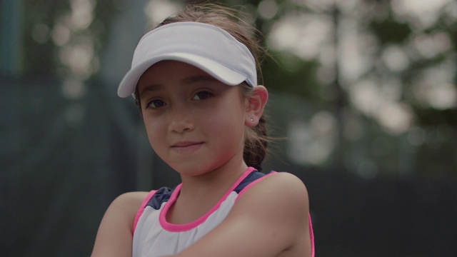 铜。运动小女孩的肖像，站在网球场对着镜头微笑视频下载