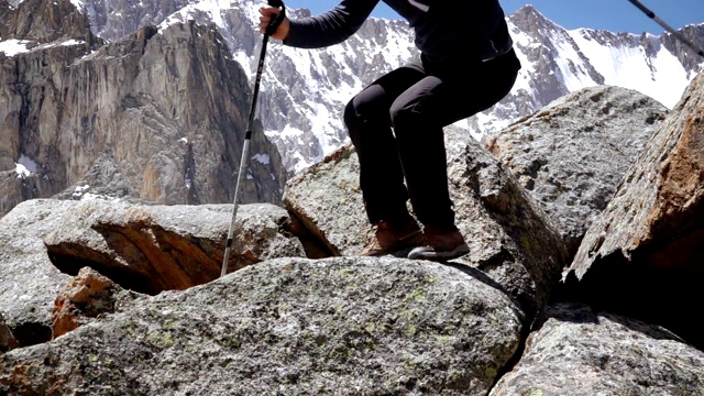 一个登山者从一块大石头上跳下来视频下载