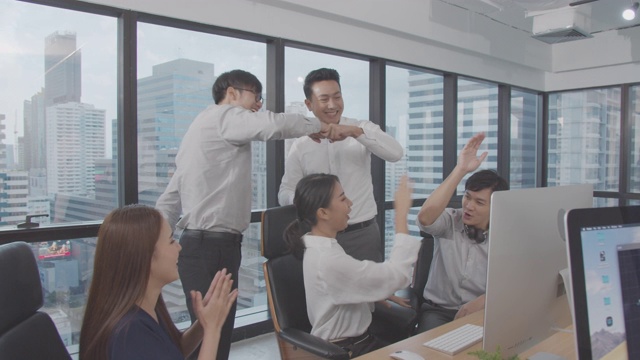 4K分辨率快乐亚洲商务团队在室内现代办公室欢笑和鼓掌庆祝，亚洲商务生活视频购买