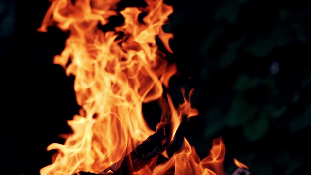 明亮的火焰从闷烧的木头在黑暗的背景。视频素材