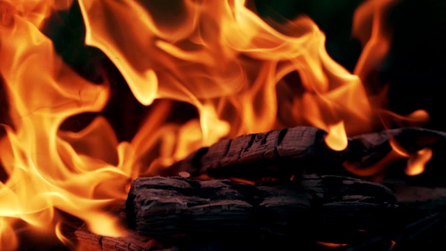 黑色的闷烧的木头，燃烧着鲜艳的火焰。视频素材