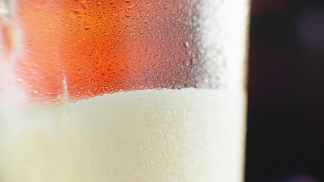 啤酒倒进有角的玻璃杯里。异丙醇在水龙头。冰镇淡啤酒在玻璃杯中与水滴。精酿啤酒形成波浪接近。新鲜和泡沫。酒吧的背景。酿酒厂精酿啤酒视频素材