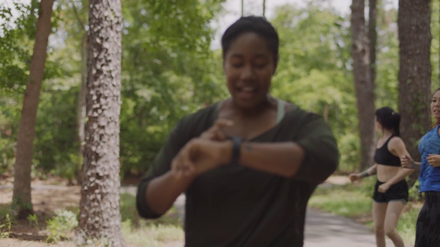 一群女运动员一起在森林里的小路上跑步，放慢速度让其他人赶上视频下载