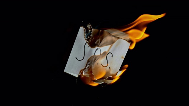 SLO MO LD白色的纸上刻有“S.O.S.”字样在火焰中燃烧视频下载