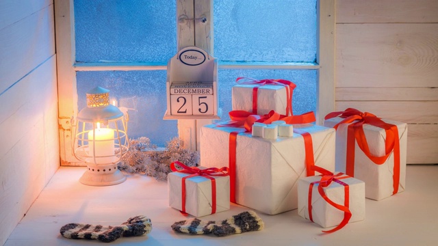 蓝色冰冻的窗户旁，白色的桌子上移动着圣诞礼物视频素材