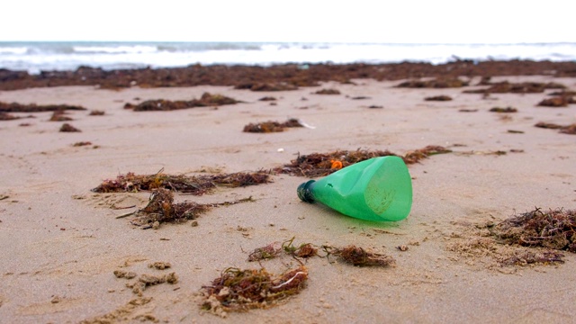 一部分绿色塑料瓶被带到沙滩上的岸边。视频素材