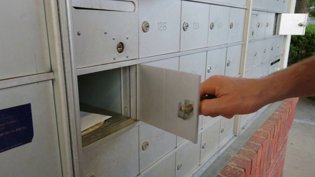 一个男人的手从邮箱里取出一封信的特写。视频素材