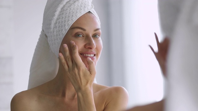 有趣的女人在脸上涂护肤霜照镜子视频素材