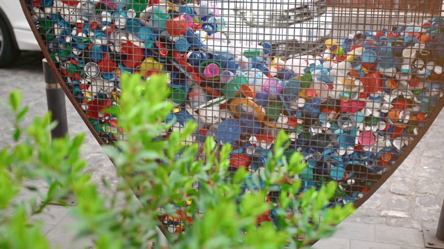 在城市中收集塑料垃圾的概念。绿色植物灌木和心形的铁笼子，用于收集宠物盖和瓶子。保护自然、污染环境的理念视频下载