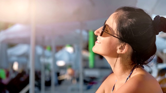 微笑晒黑的年轻女游客在暑假享受日光浴中近距离视频素材