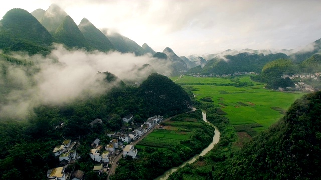 鸟瞰喀斯特山峰森林(万峰林)中的村庄和稻田，贵州，中国。视频素材