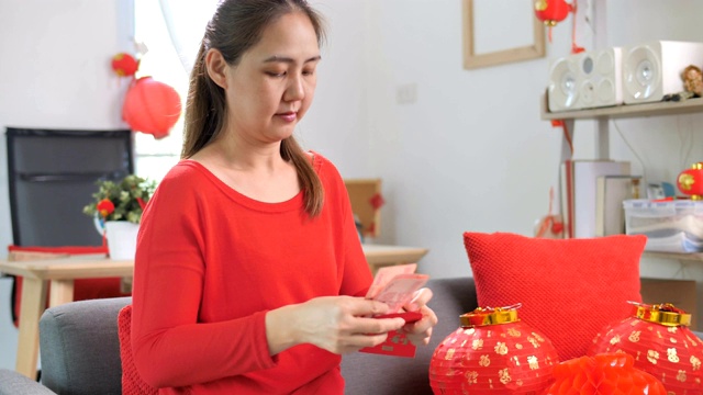 快乐的亚洲女人把钱放在红包庆祝春节视频下载