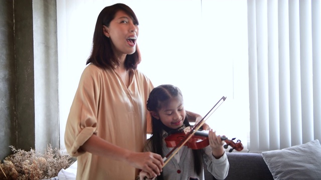 一个女人在教一个小女孩拉小提琴视频素材
