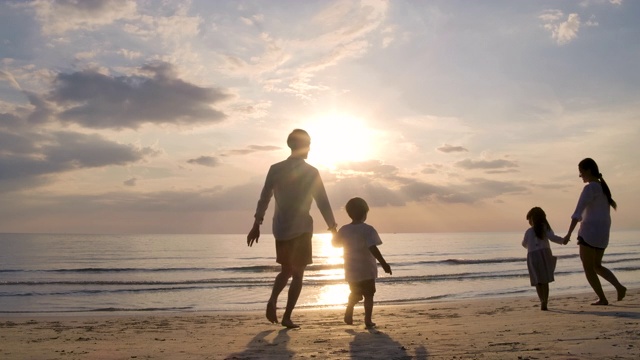 快乐的亚洲家庭在日落的海滩上跑步，旅游的概念。缓慢的运动。视频素材