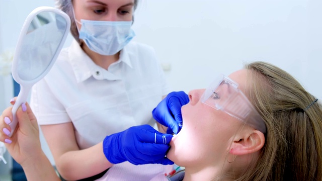 牙科医生在口腔诊所用牙线清洁女病人的牙齿。视频素材