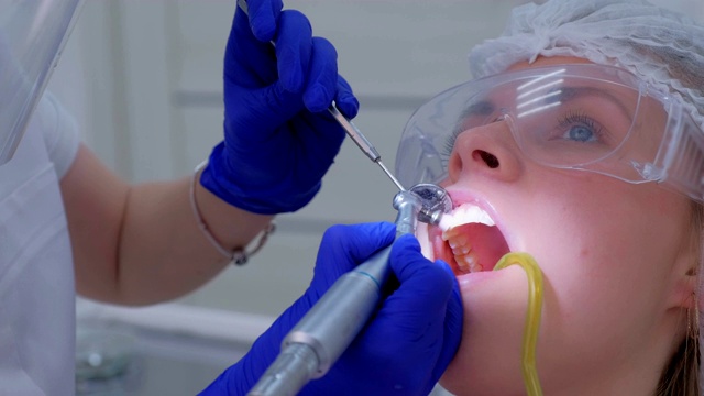 牙科医生用牙钻清洁、刷牙和抛光妇女的牙齿，近景。视频素材