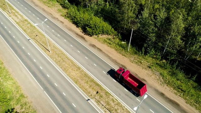 红色卡车沿着公路驶向地平线上遥远的城市视频素材